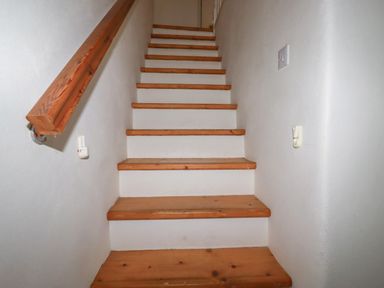 A wooden staircase with white walls and a handrail at Poldue House in Watergate near Camelford
