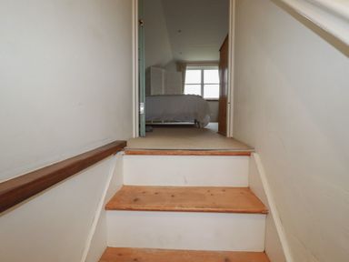 A staircase leading up to a bedroom with a bed near a window at Poldue House in Watergate near Camelford