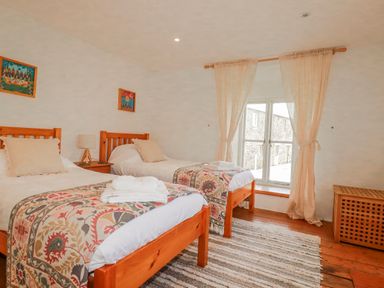 A bedroom with two beds and a window at Poldue House Watergate near Camelford