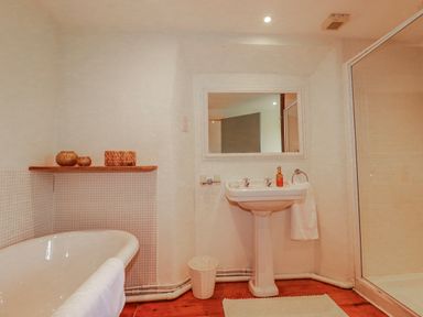 A bathroom with a bathtub, sink, and shower at Poldue House Watergate near Camelford