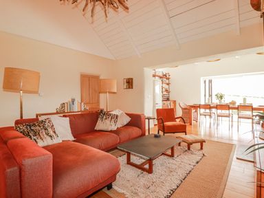 A living room with a sofa and a dining area at Roughtor Barn in Poldue near Camelford