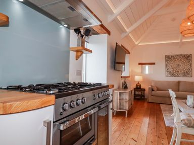 A kitchen with a stove, exhaust hood, and couch at Logan Barn Poldue near Camelford