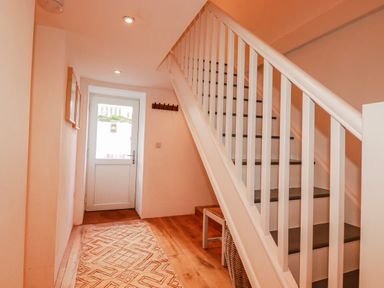 A hallway with a staircase and door at Logan Barn in Poldue near Camelford