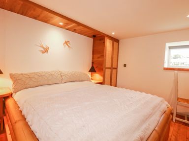 A bedroom with a bed and bedside lamps at Logan Barn in Poldue near Camelford