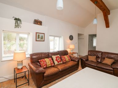 A living room with two brown leather sofas and table lamps on side tables at Bayside Cottage in Rosslare Strand County Wexford