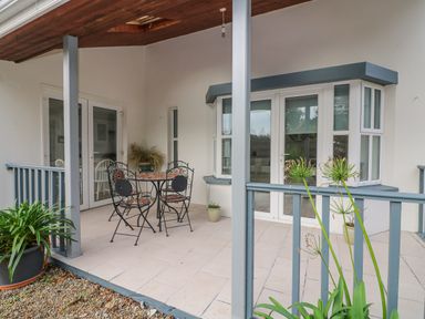 A covered outdoor patio with a metal table and chairs set surrounded by plants at Bayside Cottage in Rosslare Strand County Wexford