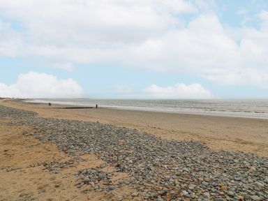 A beach with sand and pebbles next to the sea under a cloudy sky at Bayside Cottage in Rosslare Strand County Wexford