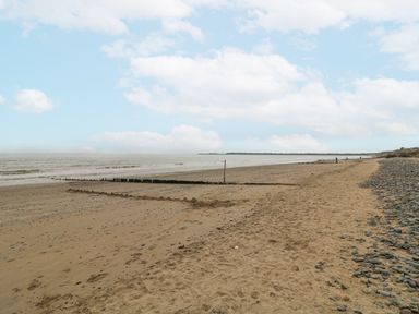 A sandy beach with scattered rocks and wooden groynes along the shoreline at Bayside Cottage in Rosslare Strand County Wexford