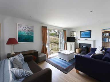 A living room with sofas a rug a coffee table a fireplace and a TV at Northern Lights in Polzeath
