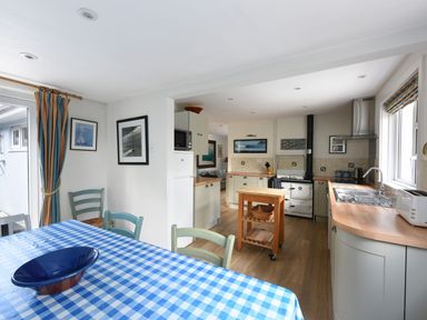 A kitchen with wooden countertops and a blue checkered tablecloth on the dining table at Northern Lights in Polzeath