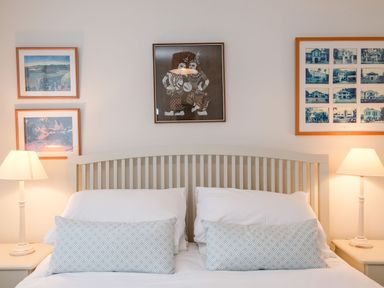 A bedroom with a double bed two patterned pillows two bedside tables with lamps and framed pictures on the wall at Northern Lights in Polzeath