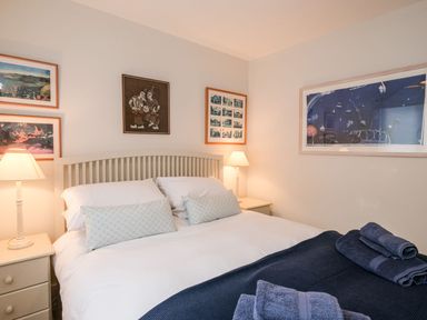 A bedroom with a double bed lamps on bedside tables and framed pictures on the walls at Northern Lights in Polzeath