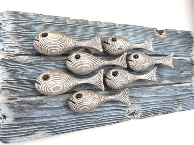 A wooden decorative wall art with seven fish figures on blue weathered wooden planks at Northern Lights Polzeath