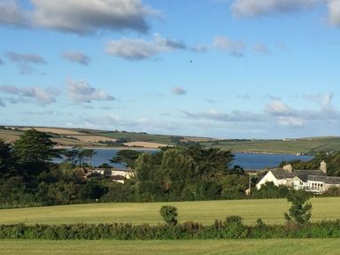 A countryside landscape with trees houses and a body of water under a partly cloudy sky at Seaworthy in Daymer Bay