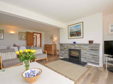 A living room with a fireplace and a coffee table at Seaworthy in Daymer Bay