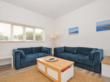 A living room with blue sofas and a coffee table at Seaworthy in Daymer Bay