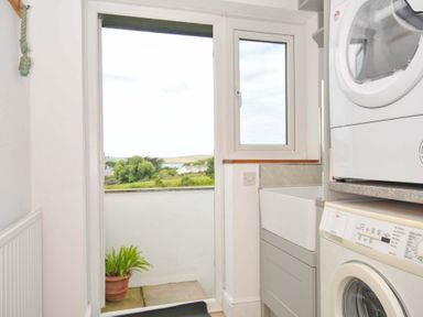 A laundry room with a washer dryer and sink at Seaworthy in Daymer Bay