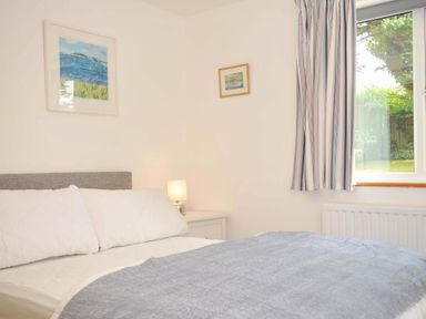 A bedroom with a bed and paintings at Seaworthy in Daymer Bay