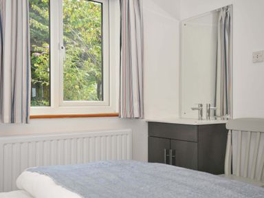 A bedroom with a window and a mirror at Seaworthy in Daymer Bay