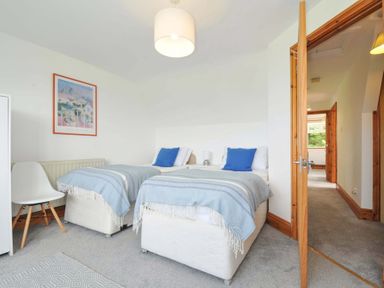 A bedroom with two beds and a chair at Seaworthy in Daymer Bay