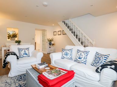 A living room with white sofas and nautical pillows near a staircase at Cwrt in Dwyran near Niwbwrch Newborough