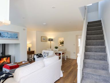 A living room with white sofas a fireplace dining table and stairs at Cwrt in Dwyran near Niwbwrch Newborough