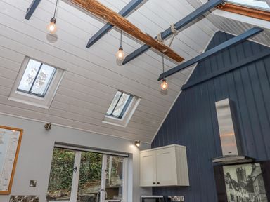 A kitchen with skylights wooden beams pendant lights and white cabinets at Alpha Cottage in Dittisham near Dartmouth
