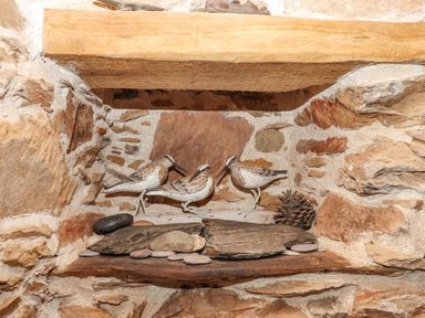 A stone alcove with three decorative bird figurines pine cone and small stones at Alpha Cottage in Dittisham near Dartmouth