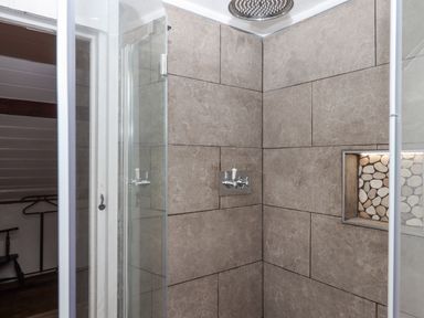 A shower area with large tiled walls and built-in niche at Alpha Cottage in Dittisham near Dartmouth