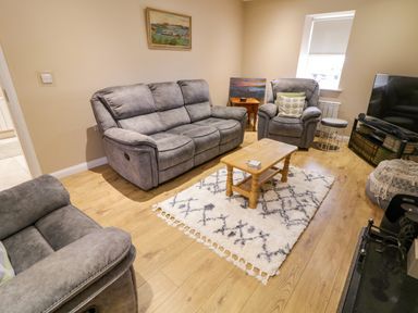 A living room with gray sofas a wooden coffee table and a patterned rug at Dock at Dominic's in Ballyheerin near Downings