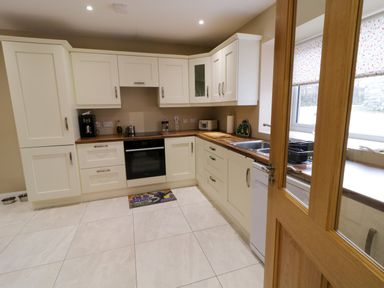 A kitchen with white cabinets and wooden countertops a stove a sink and a window at Dock at Dominic's in Ballyheerin near Downings
