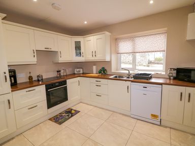 A kitchen with white cabinets wooden countertops a dishwasher oven sink and window at Dock at Dominic's in Ballyheerin near Downings