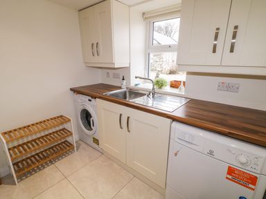 A kitchen with a washing machine, sink, dishwasher, upper cabinets, and a wooden countertop at Dock at Dominic's in Ballyheerin near Downings