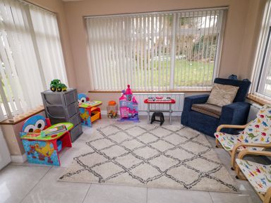 A playroom with children's toys a blue armchair and dinosaur patterned chairs at Dock at Dominic's in Ballyheerin near Downings