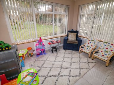 A playroom with toys a blue armchair two children's chairs with dinosaur prints and a patterned rug at Dock at Dominic's in Ballyheerin near Downings