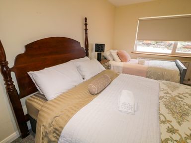 A bedroom with two beds a wooden headboard and a window with a blind at Dock at Dominic's in Ballyheerin near Downings