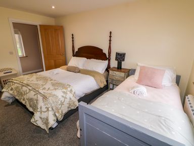 A bedroom with two beds a wooden door and a bedside table with a lamp at Dock at Dominic's in Ballyheerin near Downings