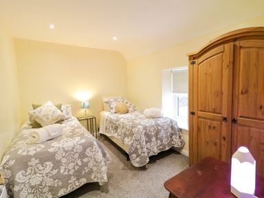 A bedroom with two single beds a wooden wardrobe and a small table lamp at Dock at Dominic's in Ballyheerin near Downings