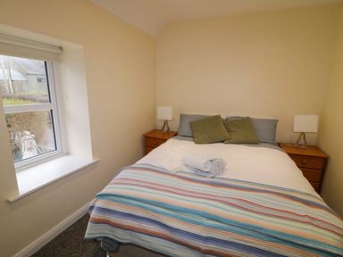 A bedroom with a double bed with striped blanket and two rolled towels on it at Dock at Dominic's in Ballyheerin near Downings