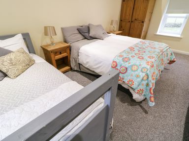 A bedroom with two beds wooden bedside tables lamps and a window at Dock at Dominic's Ballyheerin near Downings
