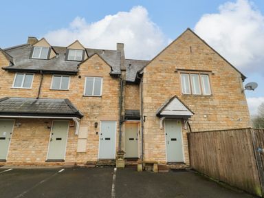 Exterior view of stone houses with light blue doors and windows by a parking area at Tree Tops in Broadway