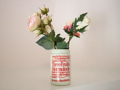 A jar with printed text used as a vase holding artificial flowers