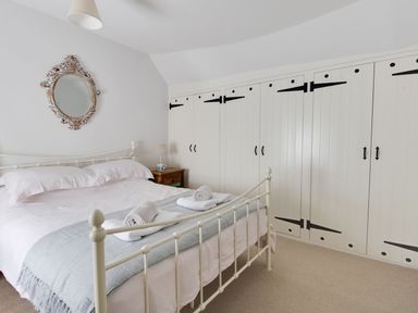 A bedroom with a metal bed frame bedside table and built in wardrobes at Amy Cottage in West Lulworth