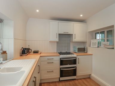 A kitchen with a sink kettle toaster microwave oven and cabinets at Stable Cottage in Lechlade-On-Thames