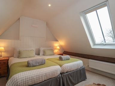 A bedroom with two single beds side by side with bedside tables and lamps and a skylight window at Stable Cottage in Lechlade-On-Thames