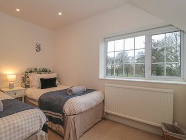 A bedroom with two single beds beside a window with trees outside at Stable Cottage in Lechlade-On-Thames