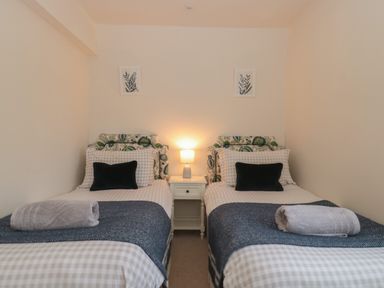 A bedroom with two single beds and a bedside table with lamp at Stable Cottage in Lechlade-On-Thames