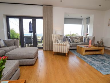A living room with sofas armchair wooden coffee table and a rug at Buzzards View in Dyserth