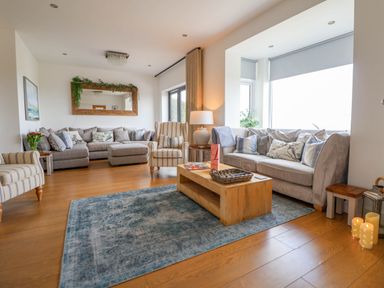 A living room with sofas armchairs a wooden coffee table mirror and candles at Buzzards View in Dyserth