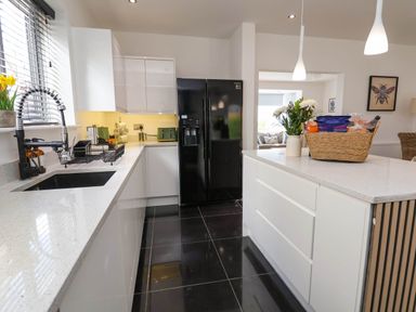 A kitchen with white cabinets black refrigerator and a countertop with a basket of groceries and flowers at Buzzards View in Dyserth